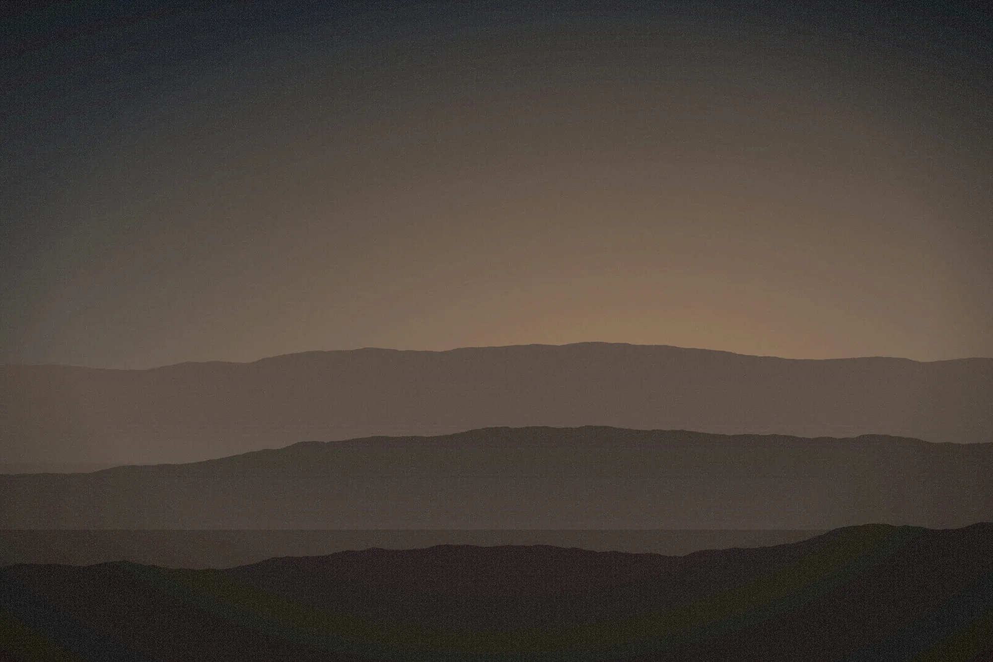 Soft brown dunes in layered bands under a dusky, rose-tinted sky.